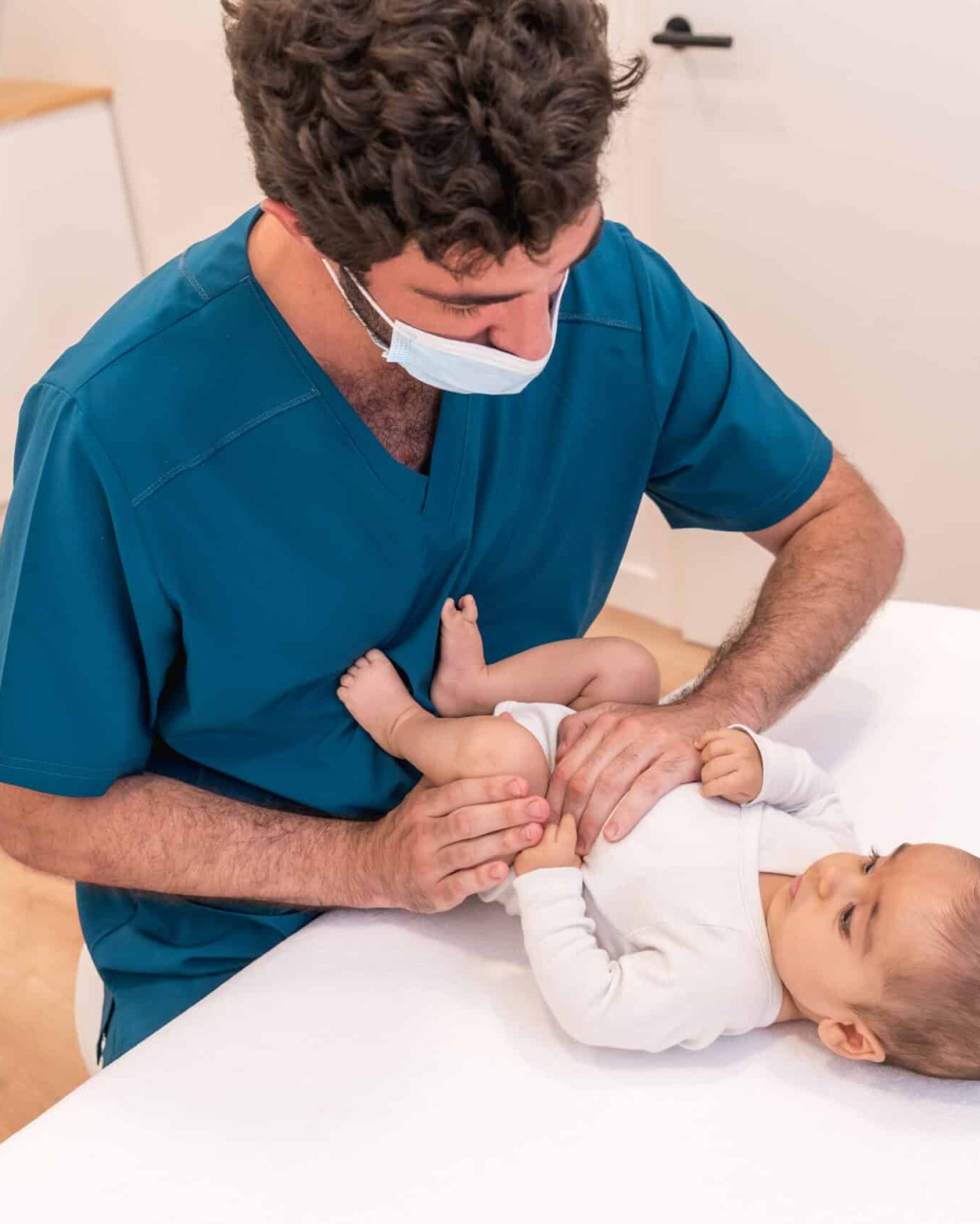 High angle view of a doctor checking up the legs of a newborn during a medical exam